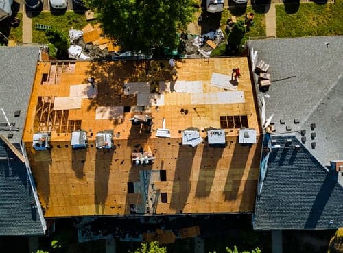 MCS Services crew mid-replacement on a Houston home, decking exposed and new underlayment going down