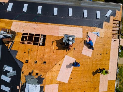 An MCS Services crew replacing a roof in Houston, decking exposed and underlayment going down
